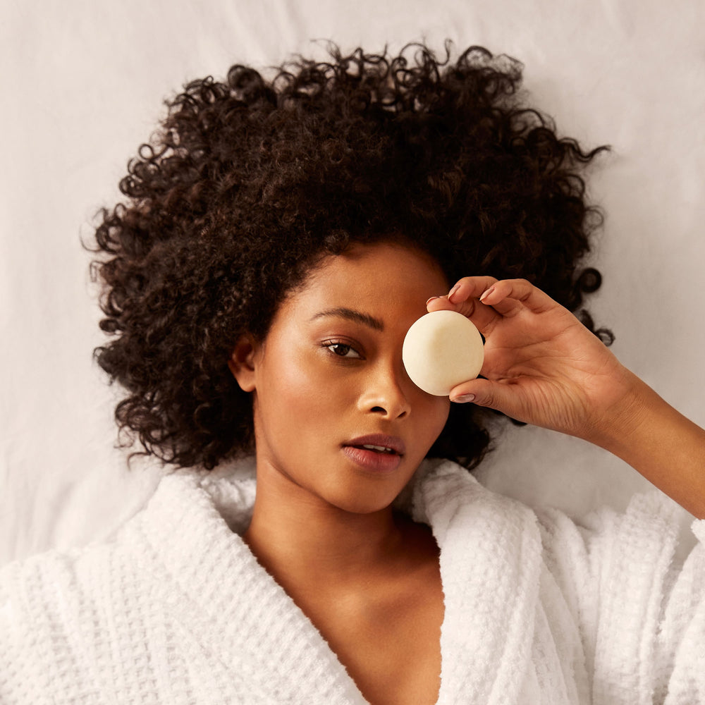 Girl Laid on a Bed Holding a Shampoo Bar