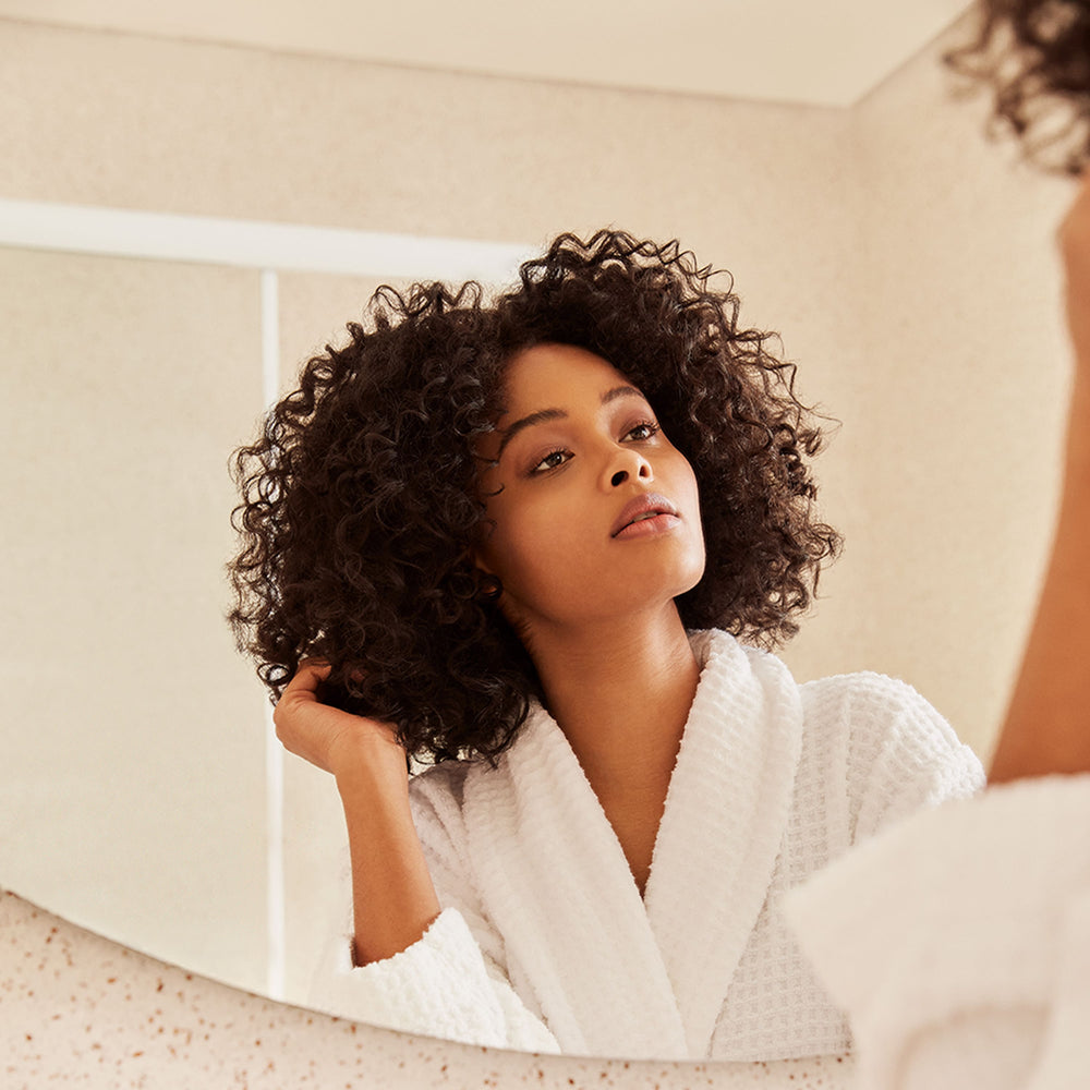 Girl looking at the mirror playing with her hair