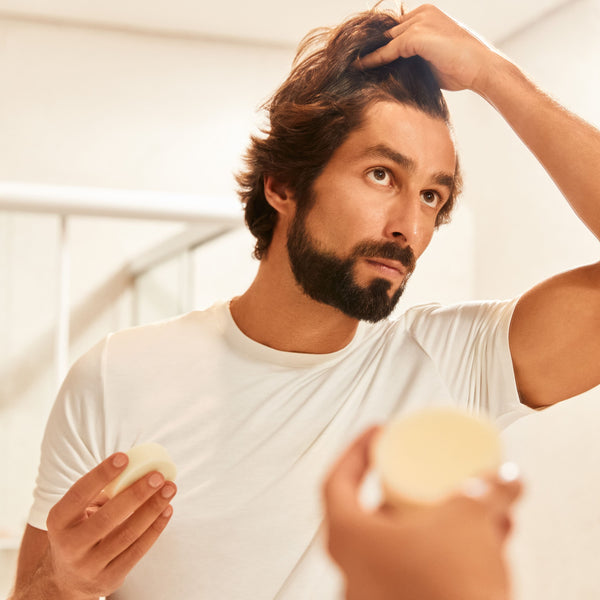 Man Holding the Ultra-Moisturizing Conditioner Bar in front of a mirror
