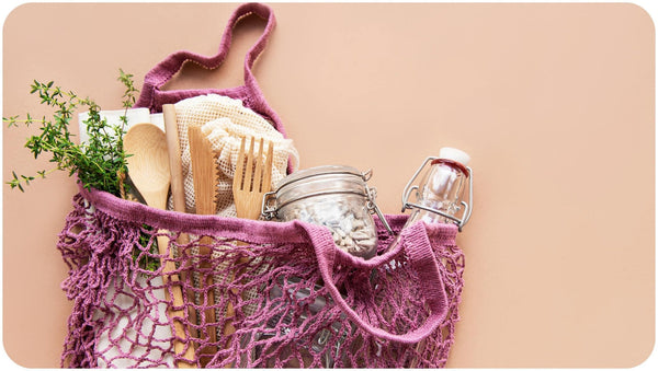 Wooden spoon, fork, glass jar and bottle in a reusable bag as a solution to how to reduce waste