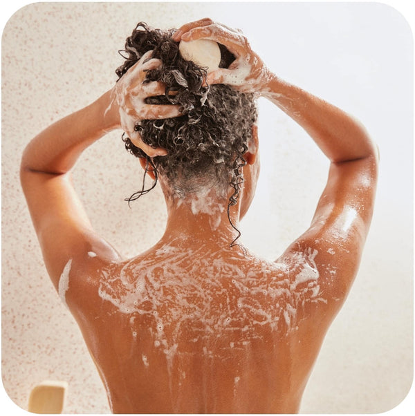 Woman in a shower using a moisturizing shampoo for curly hair