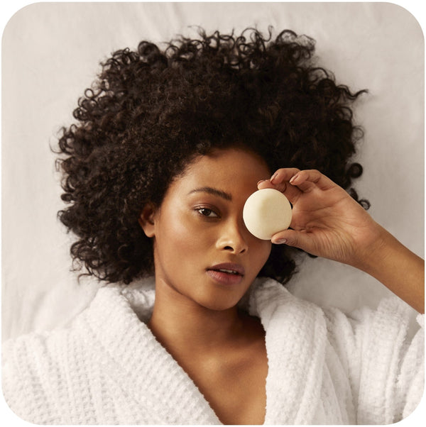 Curly-haired woman holding a Bars Over Bottles shampoo bar for curly hair  on her left eye