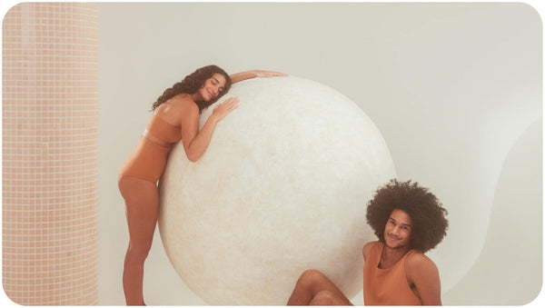 A round-shaped object between a man and a woman in dark orange outfit, who use sulfate free conditioner