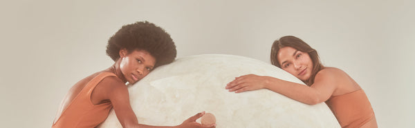 Two female models hugging a big ball—one of which is holding a shampoo bar from Bars Over Bottles